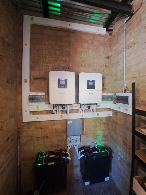 Two hybrid inverters with rack-mounted lithium batteries and a busbar box.